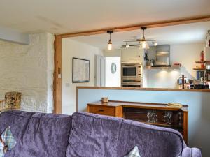 a living room with a purple couch and a kitchen at Oakwood Cottage - Glencoe in Glencoe +17 photos