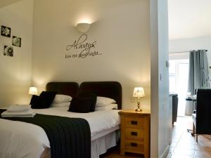 a bedroom with a bed and a sign that reads always kiss me beautiful at Caddys Cottage - Uk6714 in Lydstep