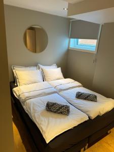 a bed with two pillows on it with a mirror at Stille leilighet med topp beliggenhet i Tromsø sentrum in Tromsø