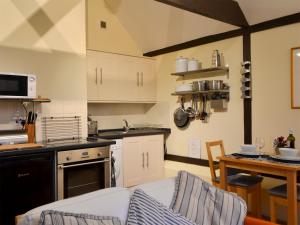a kitchen with white cabinets and a table with chairs at The Dairy in Ninfield
