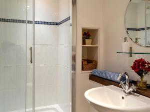 a white bathroom with a shower and a sink at The Dairy in Ninfield