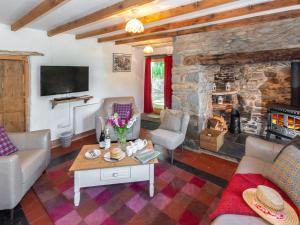 un salon avec une cheminée en pierre et une table dans l'établissement Ffynnonddewi Farmhouse - Qc1535, à Llanhowell