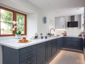 a kitchen with blue cabinets and white counter tops at The Linhay in Durleigh +17 photos