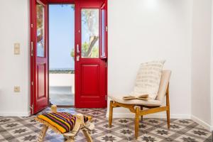 a room with a red door and a chair and a book at Sunhaus in Perissa +42 photos