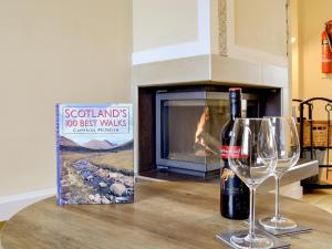 eine Flasche Wein und ein Glas auf dem Tisch mit Kamin in der Unterkunft Jessamine Cottage in Blairgowrie