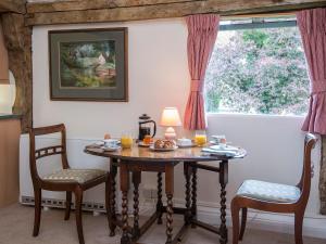 a table with two chairs and a lamp and a window at Pheasants Hill Old Byre in Hambleden