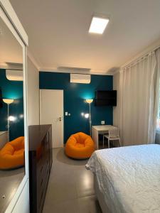 a bedroom with a bed and orange chairs and a table at 4 quartos Conforto e silêncio no coração de BH in Belo Horizonte