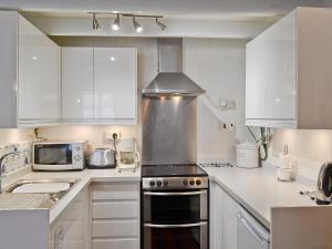 a kitchen with white cabinets and a stove top oven at Castleton House in Staithes