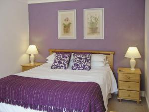 a bedroom with a bed with purple walls and two lamps at Moorhen Cottage - E3750 in Leverton