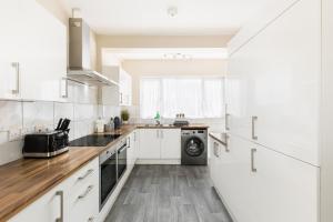 La cuisine est équipée de placards blancs et d'un lave-vaisselle. dans l'établissement Contractors-Sleeps 7-FreeWiFi-CityCentre, à Spon End 25 autres photos