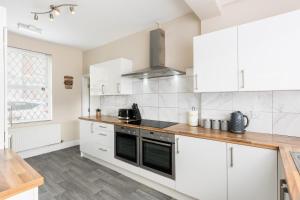 une cuisine avec des armoires blanches et un four à plaques de cuisson dans l'établissement Contractors-Sleeps 7-FreeWiFi-CityCentre, à Spon End