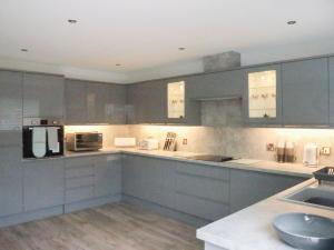 a large kitchen with gray cabinets and appliances at 2 Mote View- Uk37496 in Sandhead