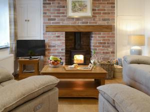a living room with a fireplace and a coffee table at Eithinog Ganol in Llandwrog