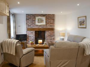 a living room with two chairs and a fireplace at Eithinog Ganol in Llandwrog