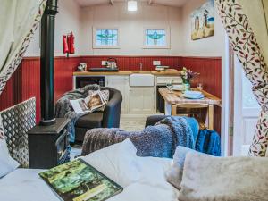 a living room with a stove and a kitchen at Goosewing Hut-Qu7072 in Melton Constable