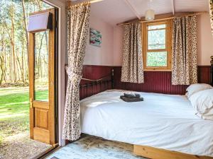 a bedroom with a bed and a window at Goosewing Hut-Qu7072 in Melton Constable