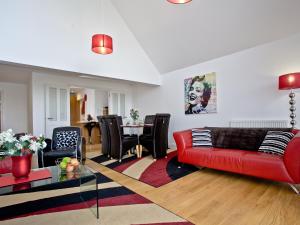 a living room with a red couch and a table at Bredon Court, Poseidon Penthouse in Newquay