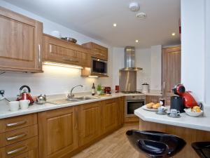 a large kitchen with wooden cabinets and a sink at Bredon Court, Poseidon Penthouse in Newquay