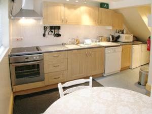 a kitchen with wooden cabinets and a table and a stove at Jebel Kasr in Braithwaite