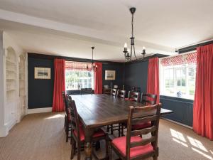 a dining room with a wooden table and red curtains at Cravens Manor in Sotherton +24 photos