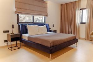 a bedroom with a bed with a blue headboard and a window at Nusa Apartments Monte Cara in Mindelo