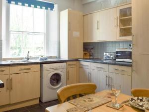 a kitchen with a washing machine and a table with chairs at Lake View Apartment in Bowness-on-Windermere
