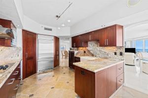 a large kitchen with wooden cabinets and appliances at Spacious Three-Bedroom Oceanfront Apartment with Panoramic Views in Pompano Beach