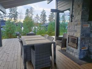 eine Terrasse mit einem Holztisch und einem Kamin in der Unterkunft Naava Resort Luppo - Upea huvila järvinäkymällä in Ähtäri