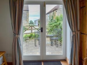an open door with a view of a patio at Dragon Fly Cottage in Brompton