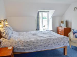 a bedroom with a large bed and a chair at Dragon Fly Cottage in Brompton +9 photos