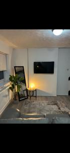 Una sala de estar con un televisor de pantalla plana en la pared. en Home away from home, en Bury