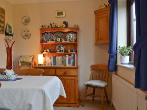 Zimmer mit einem Tisch und einem Bücherregal in der Unterkunft Ringstead Cottage in Ringstead