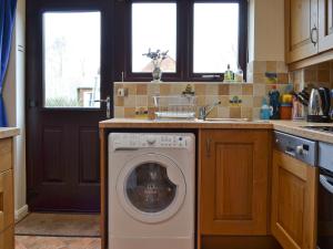 eine Küche mit Waschmaschine und Spüle in der Unterkunft Ringstead Cottage in Ringstead
