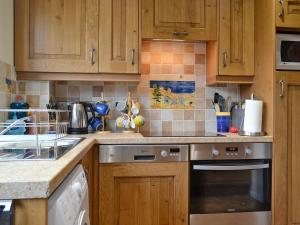 eine Küche mit Holzschränken und Geräten aus Edelstahl in der Unterkunft Ringstead Cottage in Ringstead