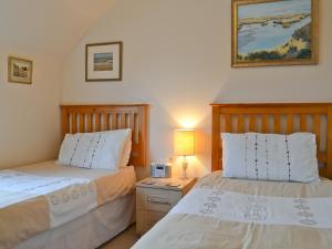 ein Schlafzimmer mit 2 Betten und einem Nachttisch mit einer Lampe in der Unterkunft Ringstead Cottage in Ringstead + 3 Fotos