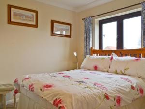 ein Schlafzimmer mit einem Bett mit geblümter Tagesdecke in der Unterkunft Ringstead Cottage in Ringstead