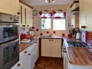 a kitchen with white cabinets and a stove top oven at The Wherry in Wroxham