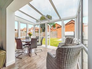 a conservatory with a table and chairs and windows at The Beach Bungalow in Beltinge