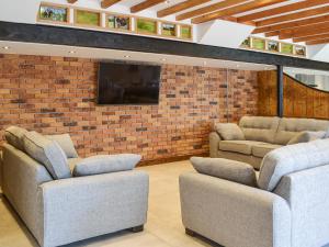 a living room with two couches and a brick wall at The Old Stables in Tickton