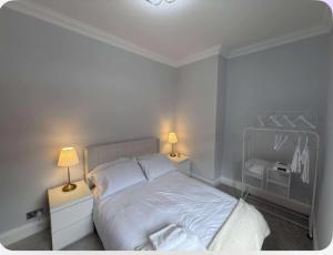 a bedroom with a white bed and two lamps at Dotty Apartment in Birtley