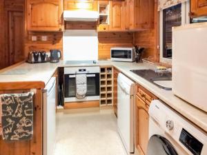 a kitchen with white appliances and wooden cabinets at Bewick Lodge in Keswick