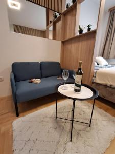 a living room with a couch and a table with a bottle of wine at Apartman Pahuljica in Pale