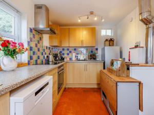 een keuken met houten kasten en een witte koelkast bij Elsie's Cottage in Pontesbury