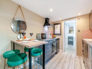 a kitchen with a bar with green stools at Vitamin Sea Residency in Herne Bay