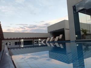 a swimming pool with chairs in front of a building at Apartamento Home Club, com dois quartos! in Foz do Iguaçu