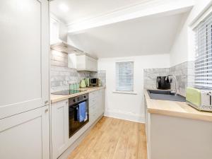 a kitchen with white cabinets and a sink at Violet Cottage - Uk45968 in Yarm +7 photos