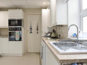 ウエストワード・ホーにあるPoint Breakの白いキャビネットとシンクのあるキッチン