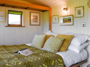a bedroom with a bed with a book on it at Shepherds Hut - Ukc6774 in Llanallgo +8 photos