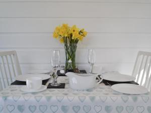 a white table with a vase of yellow flowers on it at Field House Lodge in Borrowdale Valley