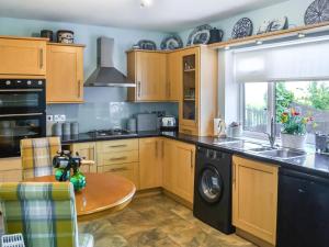 a kitchen with wooden cabinets and a round table at Grooms Cottage in Choppington